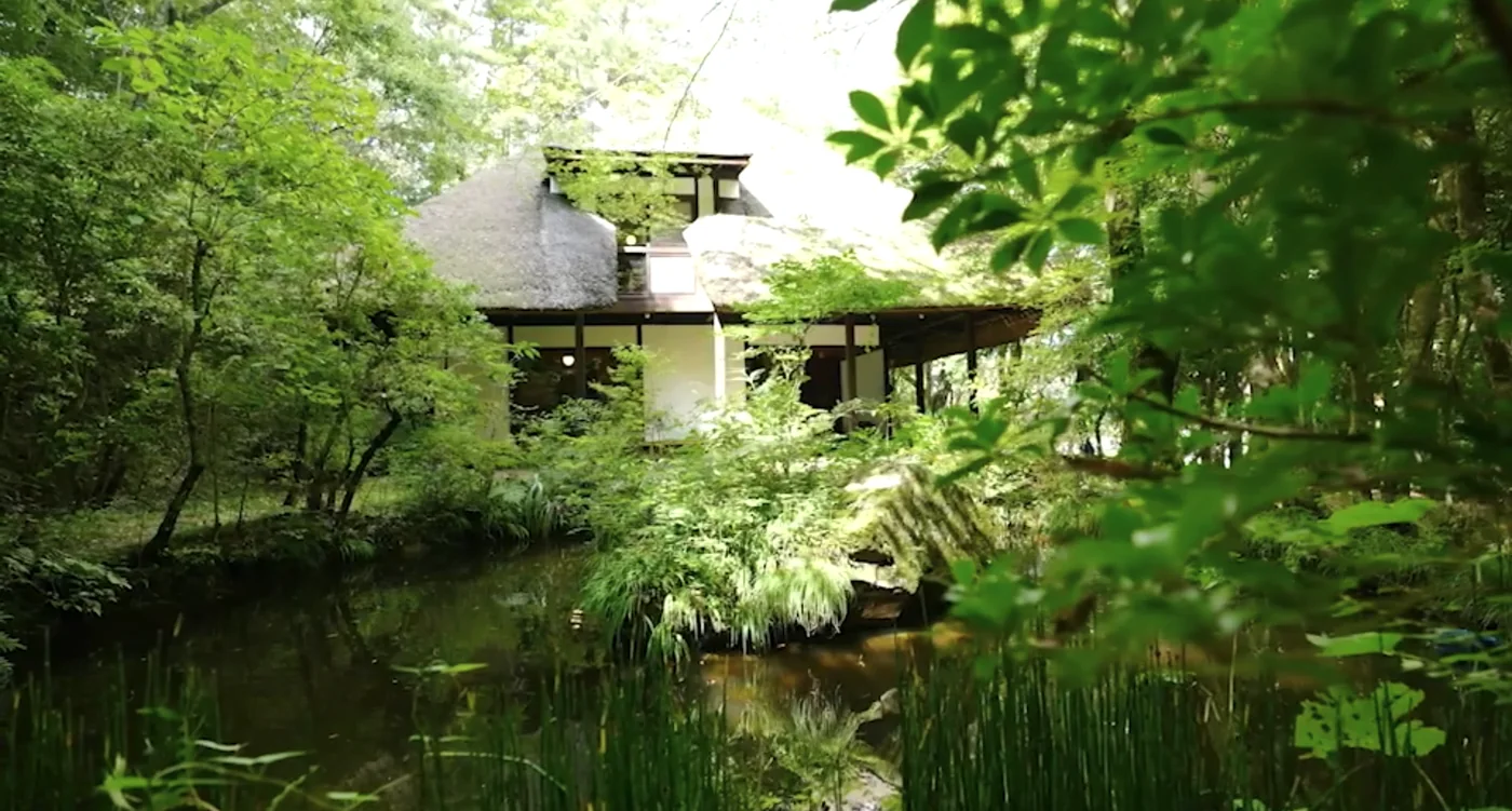 茅葺き屋根の家と池のある庭